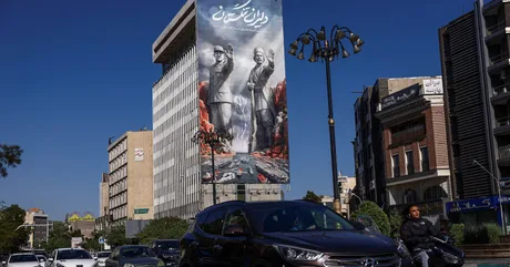 Un peisaj urban din Iran, cu clădiri și un banner mare pe fațada unei clădiri.