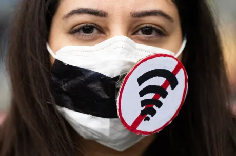 O femeie cu mască și semn care interzice accesul la internet.