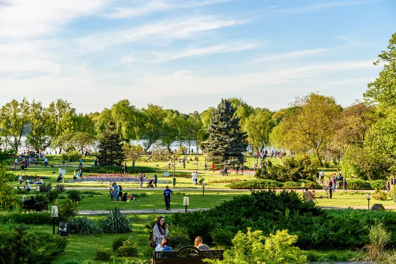 Parc verde plin de oameni care se bucură de vremea frumoasă de primăvară.
