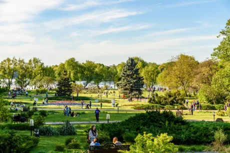Parc verde plin de oameni care se bucură de vremea frumoasă de primăvară.