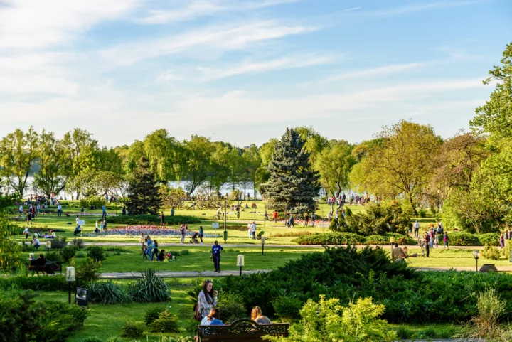 Parc verde plin de oameni care se bucură de vremea frumoasă de primăvară.