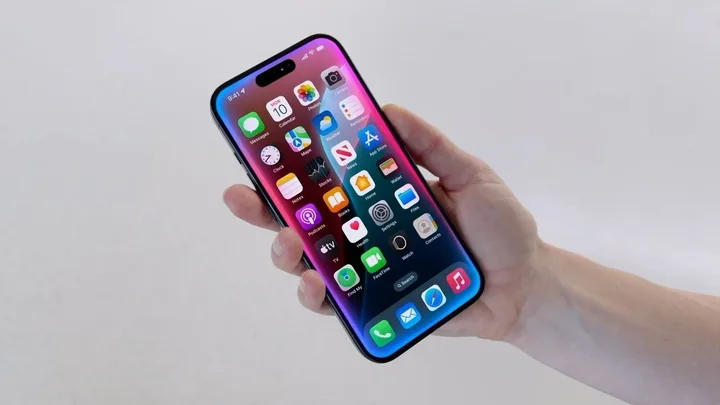 Un utilizator ține un iPhone cu ecran colorat și aplicații deschise.