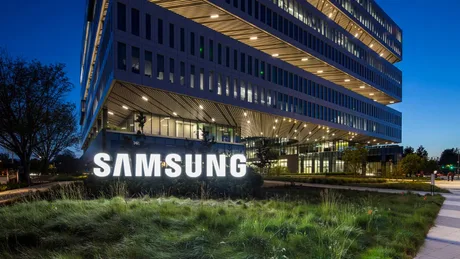 Sediul Samsung Electronics iluminat noaptea, cu vegetație în prim-plan.
