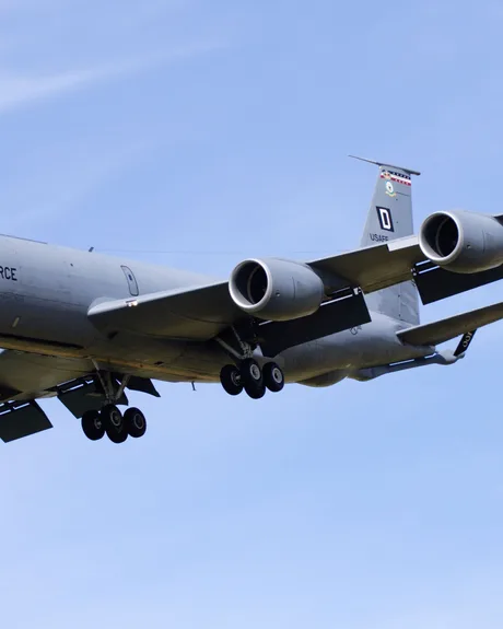 Avion militar american de realimentare în zbor, cu fundal albastru.