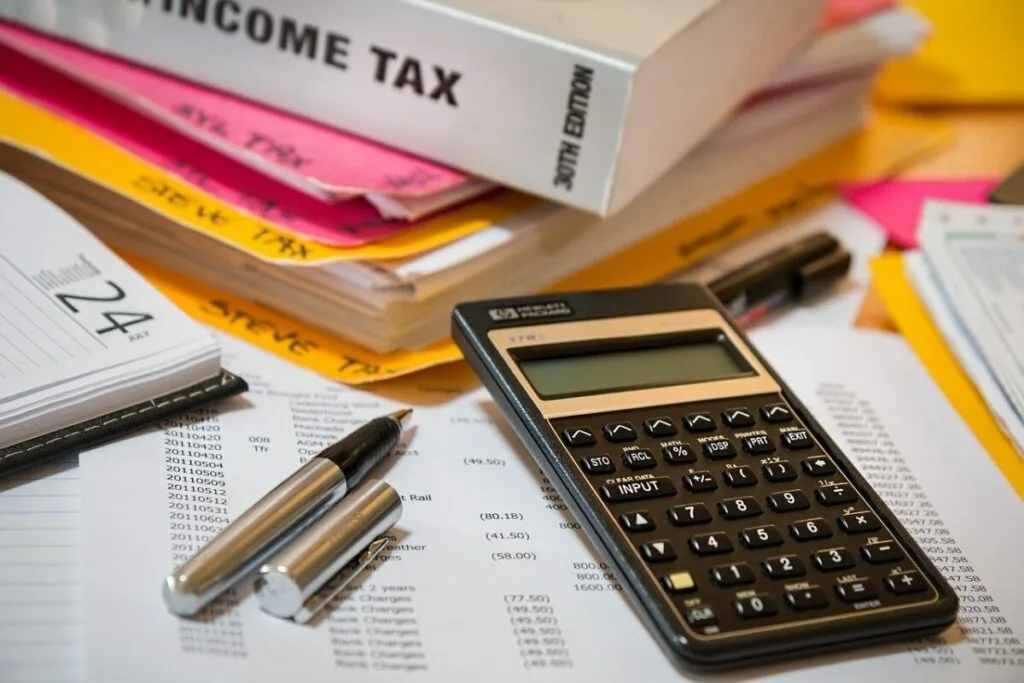 Calculatoare și documente financiare pe un birou, simbolizând analiza economică.