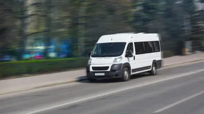 Microbuz electric în mișcare pe o stradă urbană.