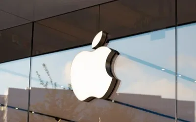 Logo Apple reflectat pe o fațadă modernă de sticlă.