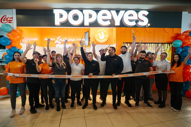 Angajați și clienți sărbătoresc deschiderea unui restaurant Popeyes.