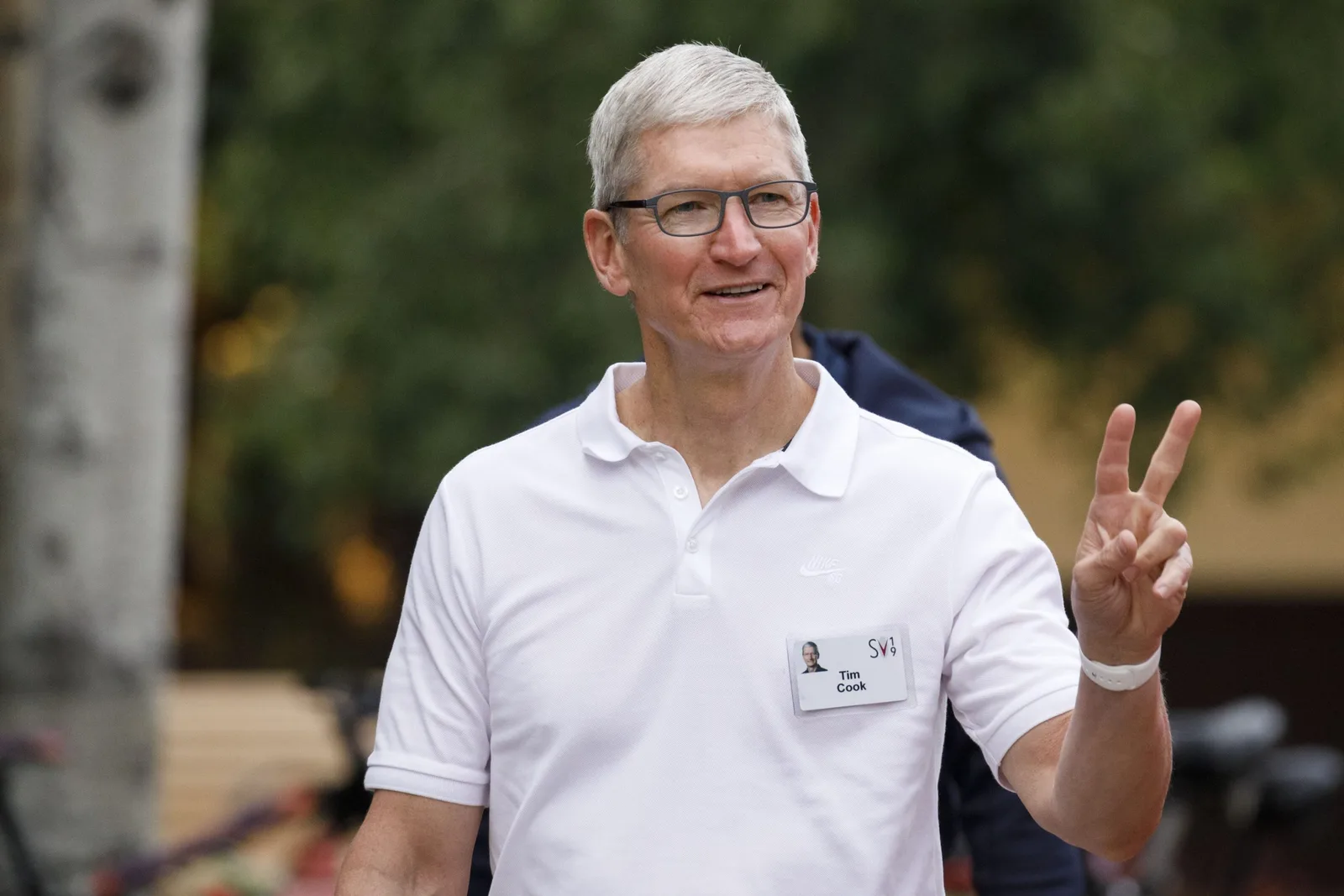 Tim Cook zâmbind și făcând semnul păcii în aer liber.