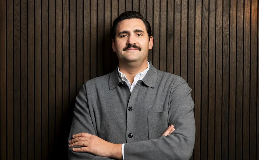 Wiktor Stopa, noul lider în marketing la Revolut, zâmbește în fața unei pereți din lemn.