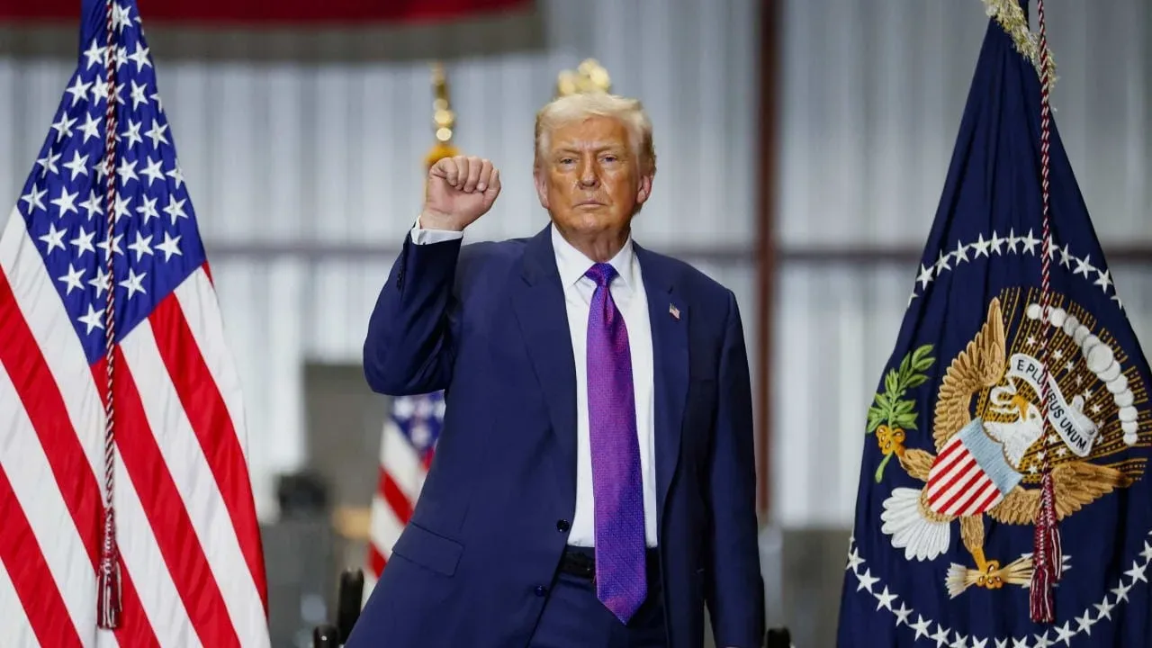 Donald Trump salutând în fața steagurilor americane, într-un cadru oficial.