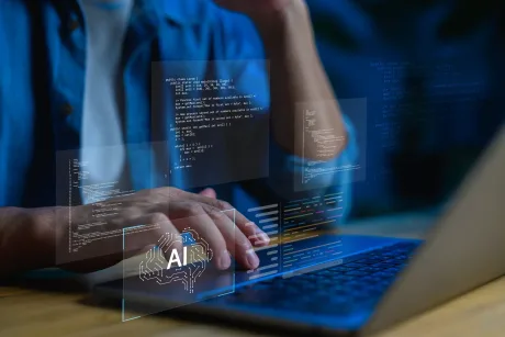 Persoană lucrând la un laptop cu cod AI vizibil.