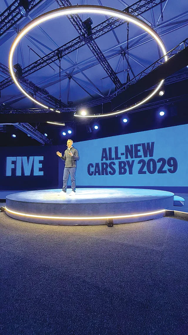 Prezentare pe scenă cu un bărbat vorbind despre viitorul automobilelor electrice.