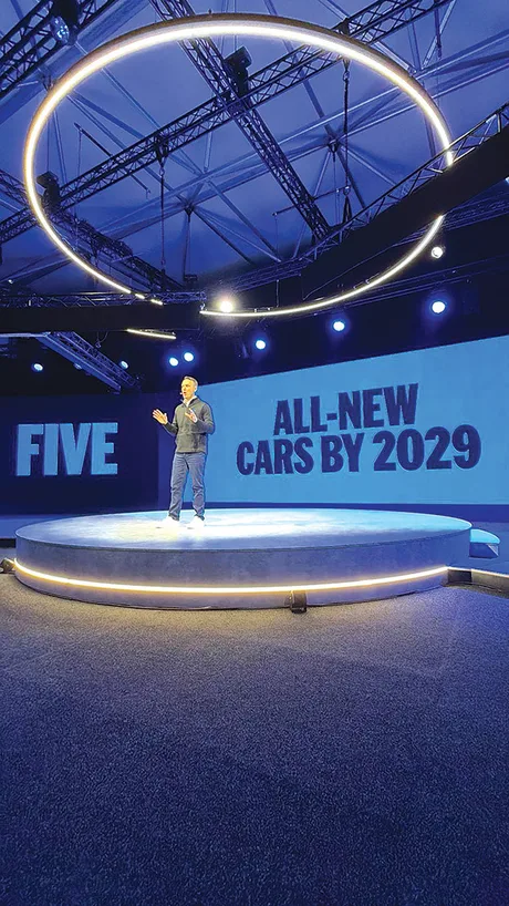 Prezentare pe scenă cu un bărbat vorbind despre viitorul automobilelor electrice.