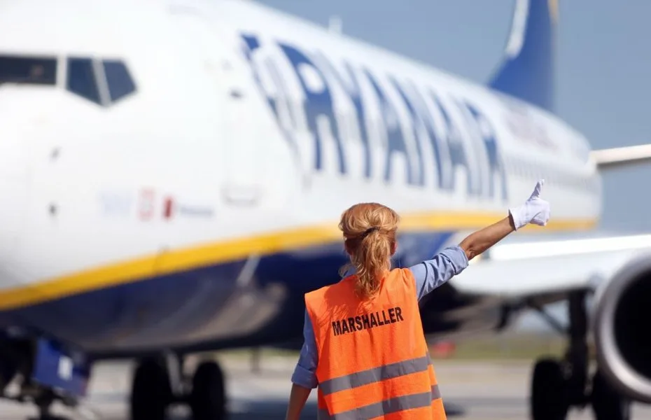 Un angajat dirijează un avion Ryanair pe aeroport.