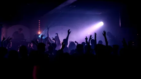 Participanți la un festival rave, dansând sub lumini colorate.