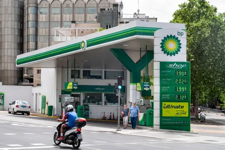 Stație de benzină BP cu prețuri afișate și clienți la cumpărături.