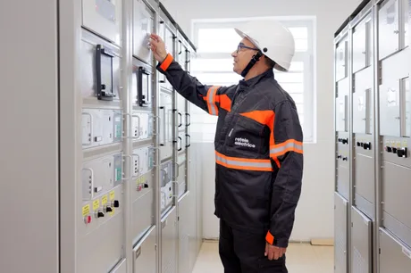 Tehnician verificând echipamente electrice într-o stație de distribuție modernizată.