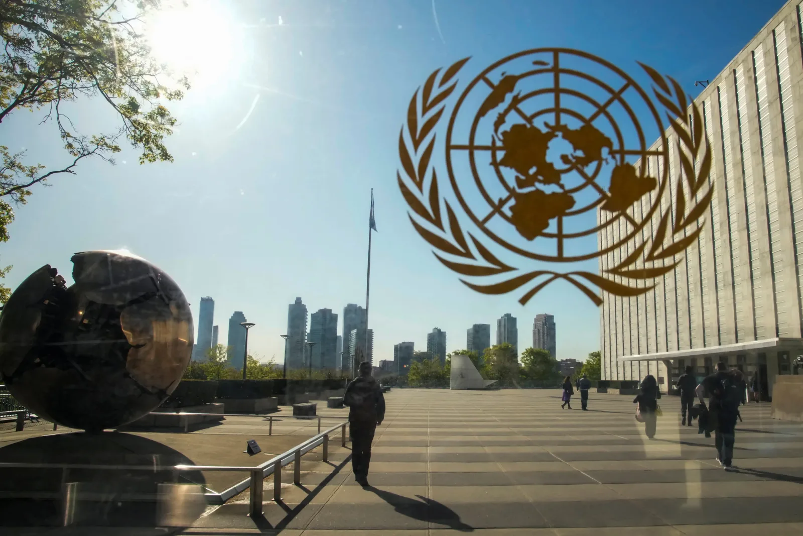 Sediul ONU cu simbolul organizației și clădiri moderne în fundal.