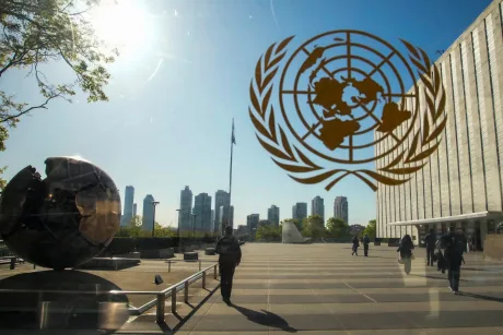 Sediul ONU cu simbolul organizației și clădiri moderne în fundal.
