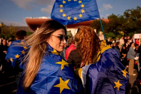 Participanți la marșul pro-Europa, purtând steaguri și simboluri europene.