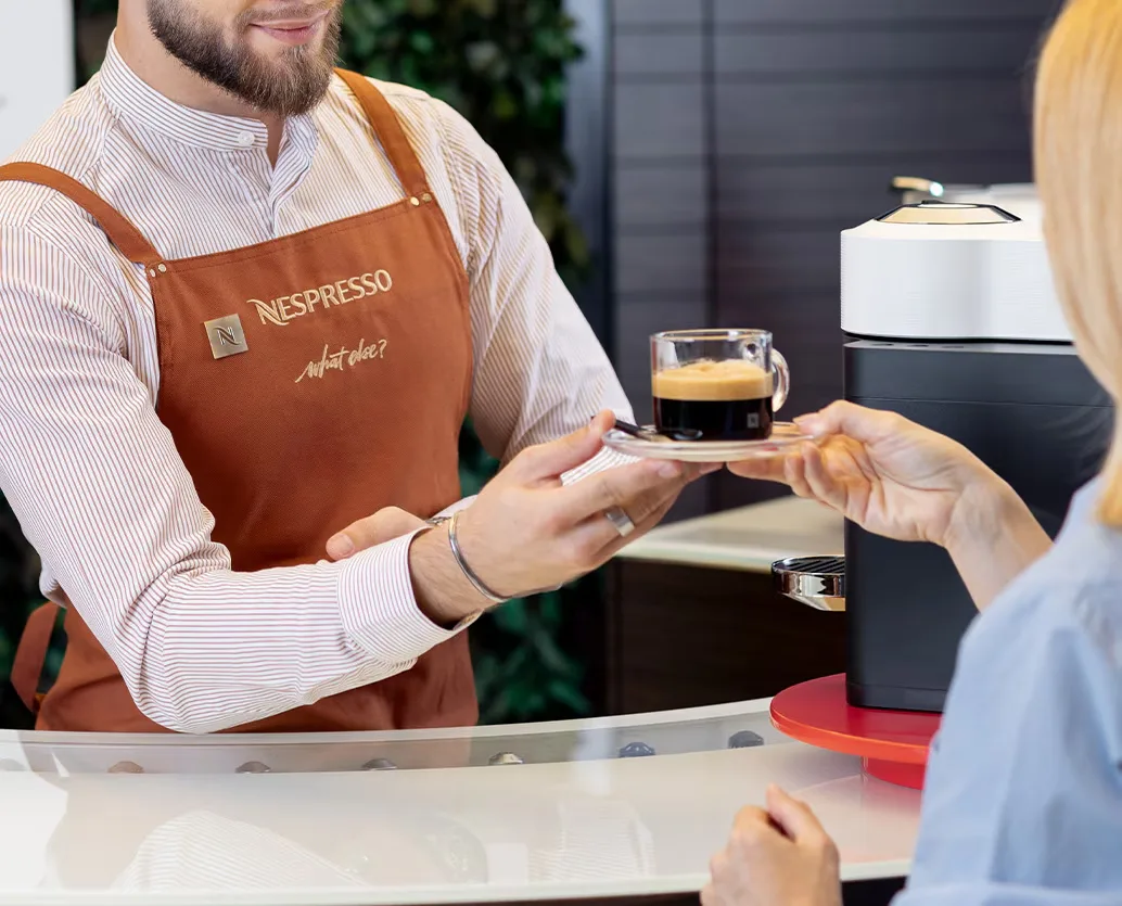 Barista oferind o cafea proaspăt preparată clienților în noul pavilion Nespresso.