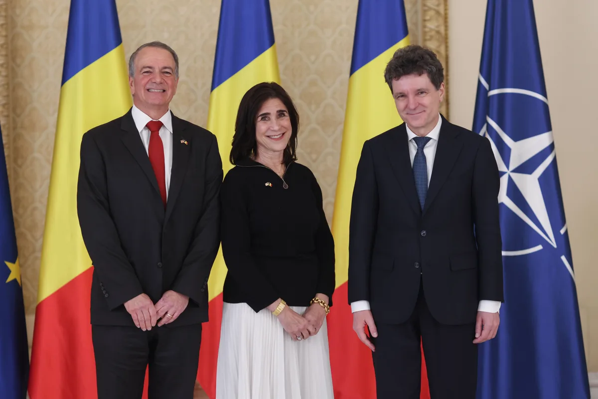 Ambasadorul SUA la București alături de oficiali români în fața drapelului național.