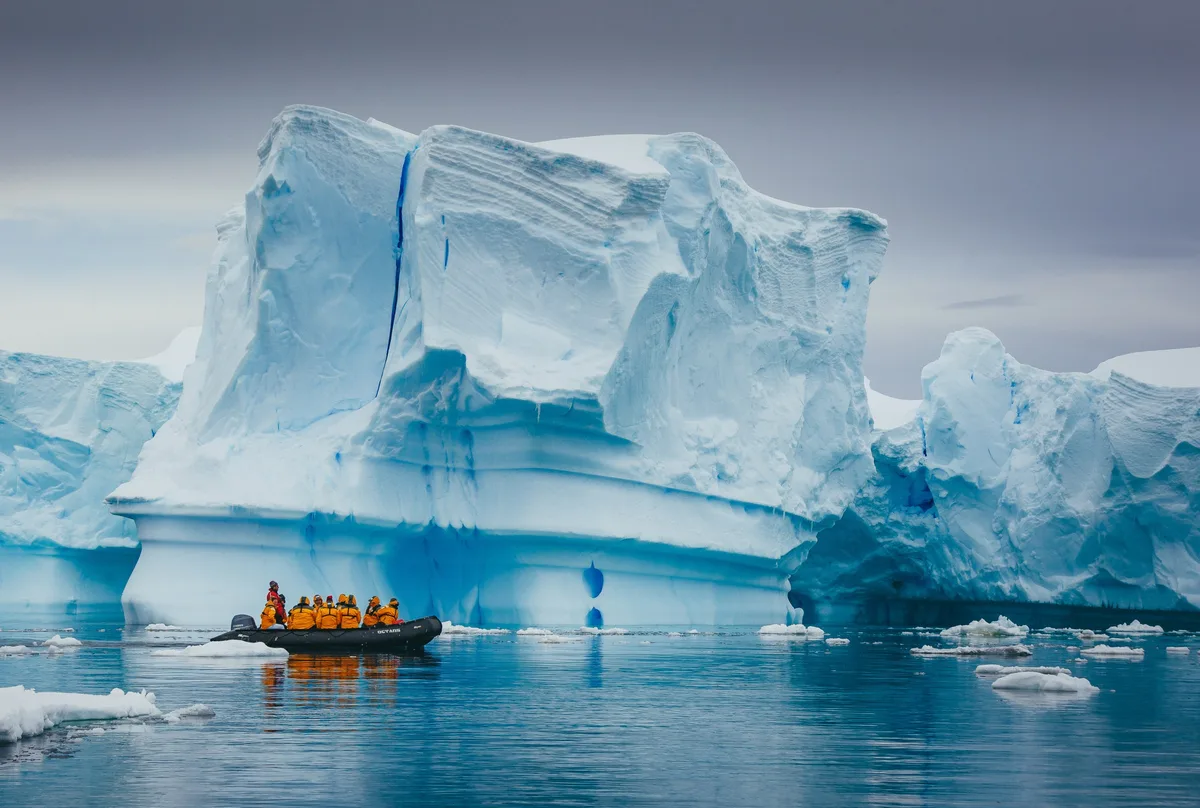 Peisaj glaciar din Antarctica cu un grup de cercetători.