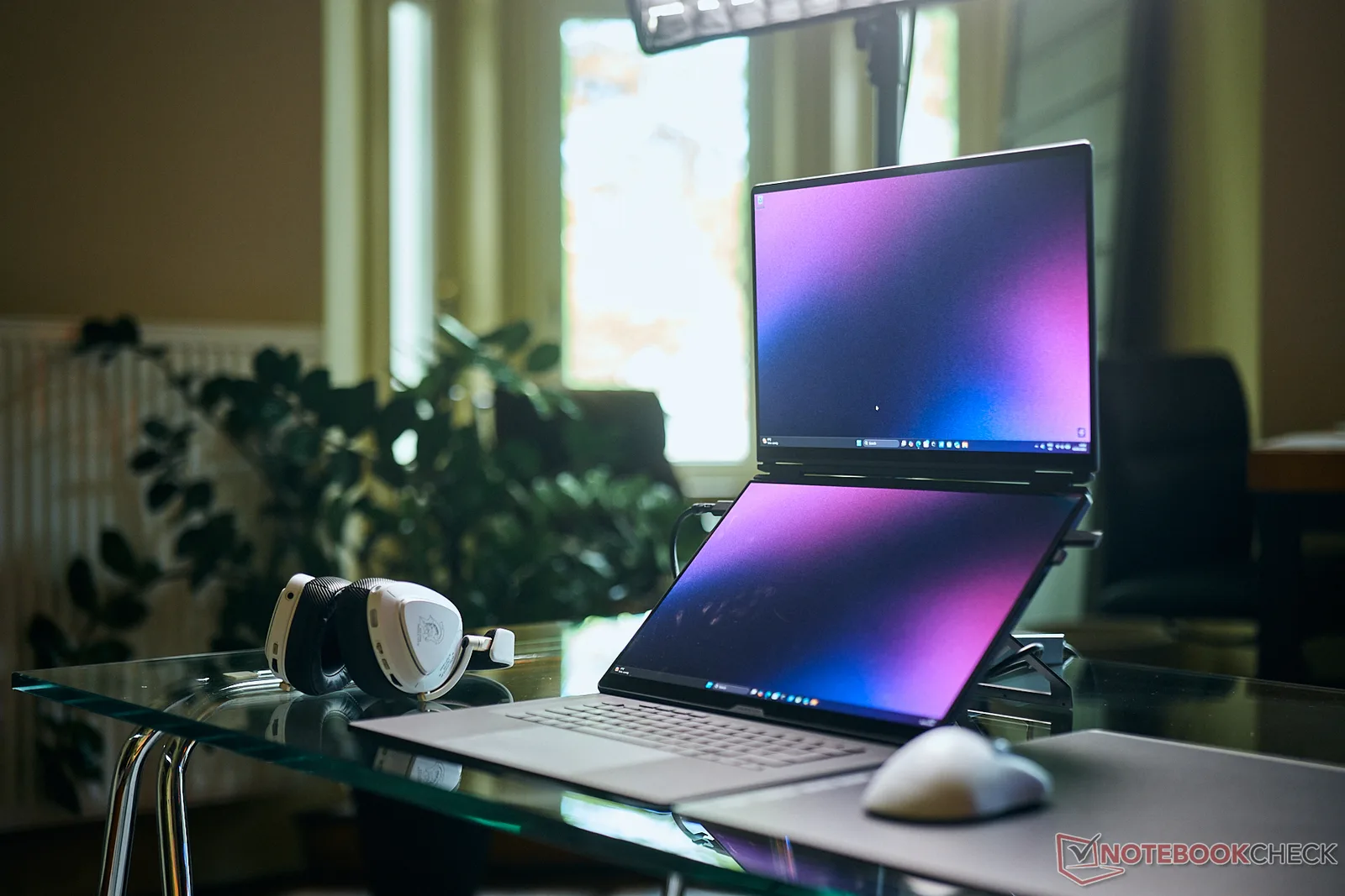 Laptop cu două ecrane OLED, design modern și accesorii de gaming.