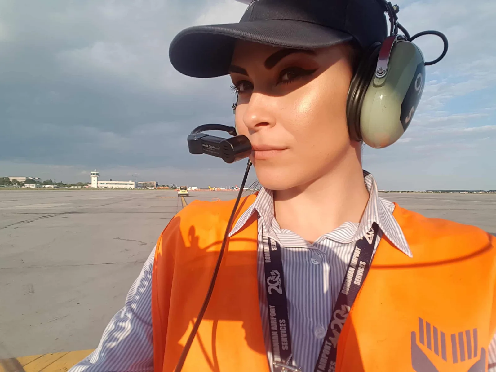 Persoană pe pista aeroportului, purtând echipament de siguranță și căști.