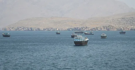 Vaporase ancorate în Strâmtoarea Hormuz, pe fundal montan.