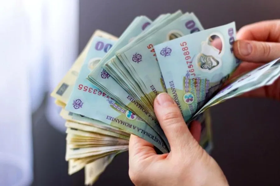 Bancnote românești în mână, simbolizând schimbările salariale.