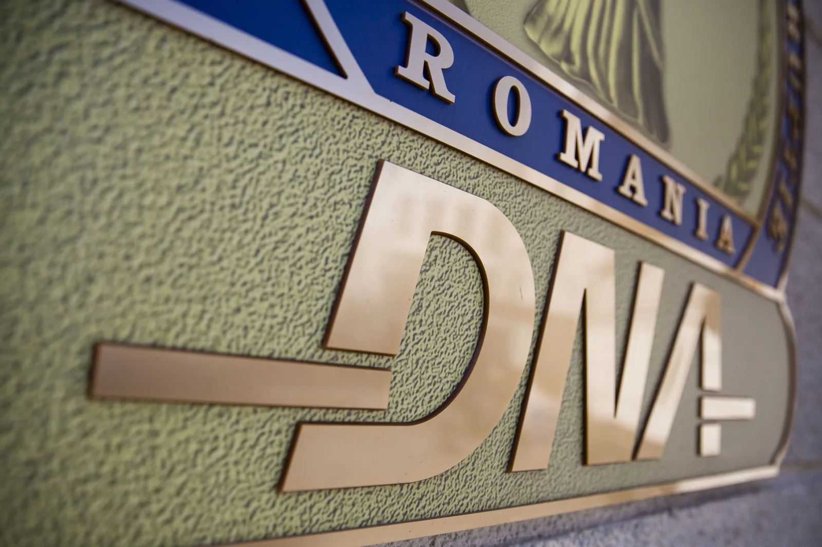 Sigla DNA pe un fundal texturat, simbol al luptei împotriva corupției.