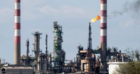 Instalații industriale cu fum și flacără, simbolizând criza energetică.