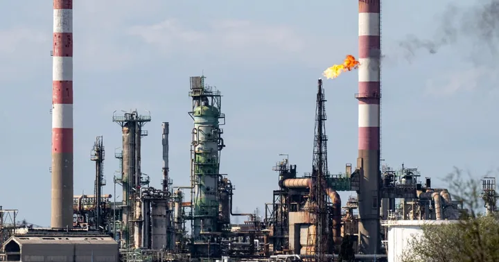 Instalații industriale cu fum și flacără, simbolizând criza energetică.