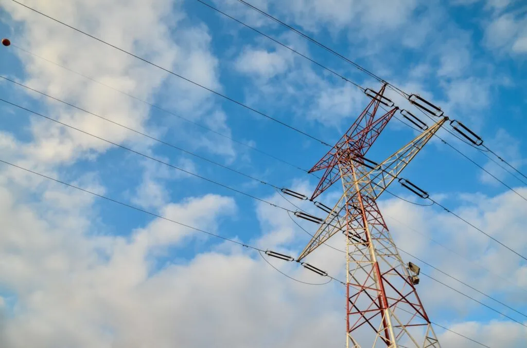 Turn de electricitate pe fundal de cer senin cu nori albi.