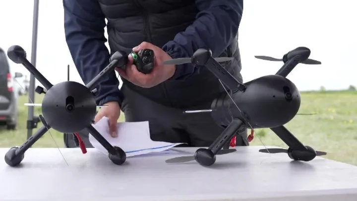 Un bărbat pregătește drone pentru utilizare pe un birou în aer liber.