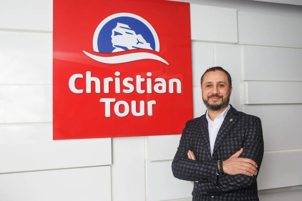 Cristian Pandel, fondatorul Christian Tour, în fața logo-ului companiei.