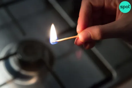 O mână aprinde o chibrit pe un aragaz, simbolizând energia.