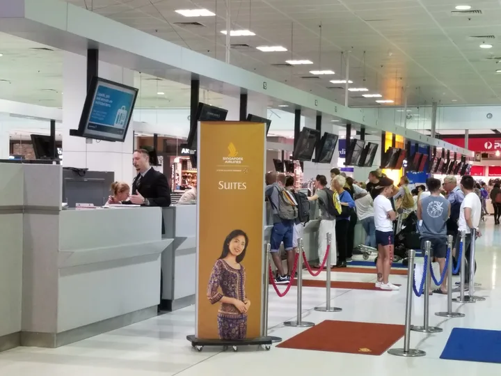Pasageri așteptând la ghișeul de check-in într-un aeroport modern.