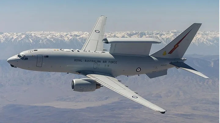 Aeronava Boeing E-7A în zbor, cu peisaj montan în fundal.
