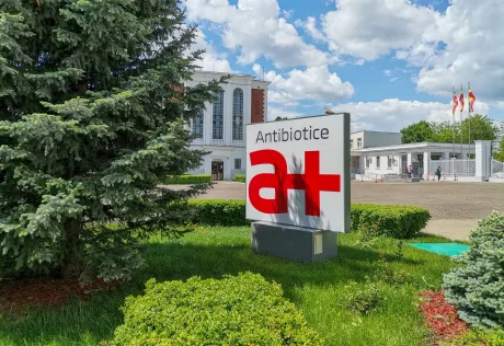 Logo-ul Antibiotice Iași pe fond verde, cu cer senin și nori albi.