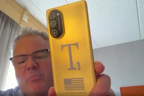Un bărbat ține un telefon Trump T1 cu un design nou și logo-ul steagului SUA.