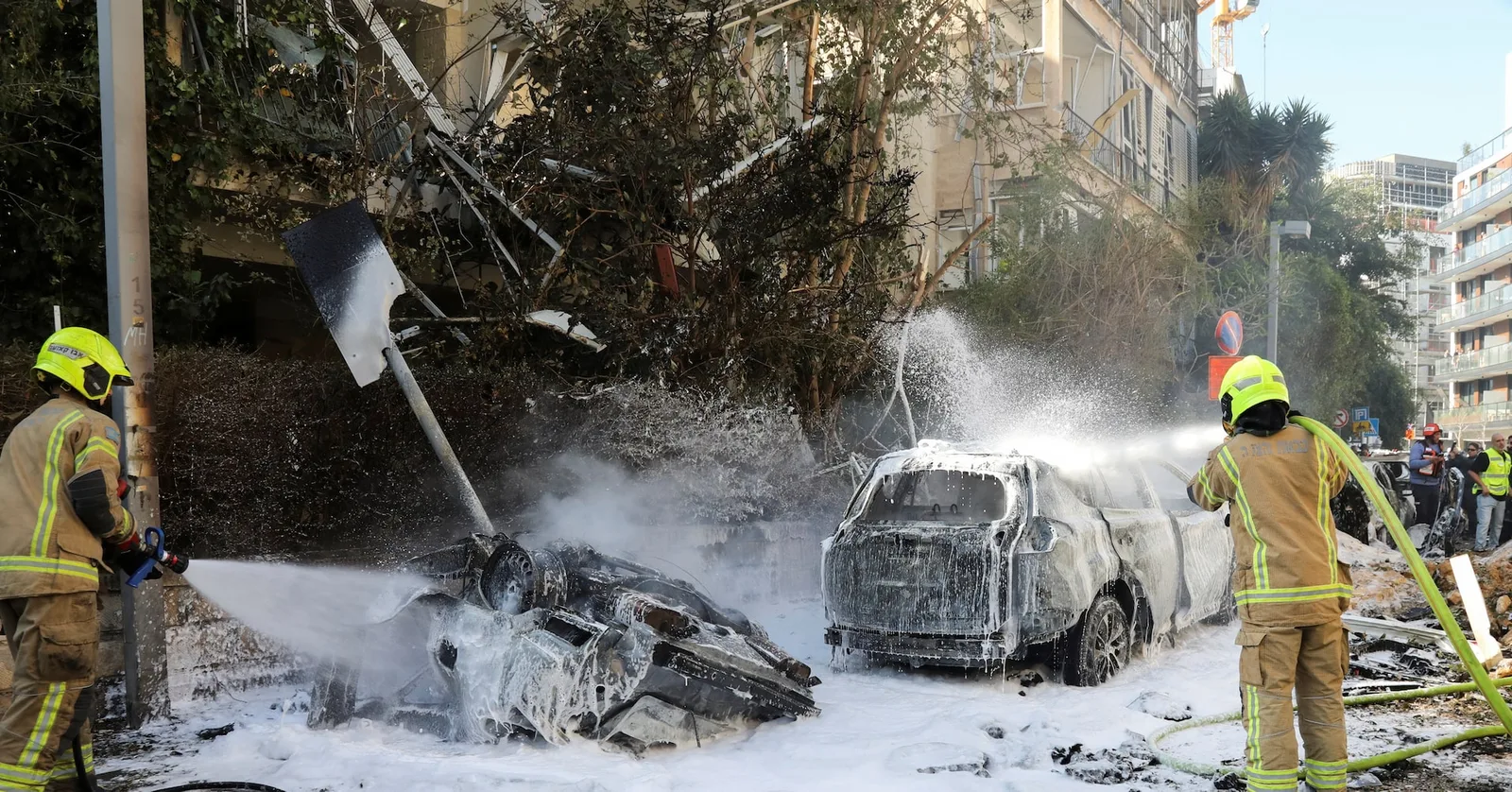 Pompierii stropesc cu apă vehicule avariate după un atac cu rachete.