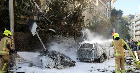 Pompierii stropesc cu apă vehicule avariate după un atac cu rachete.