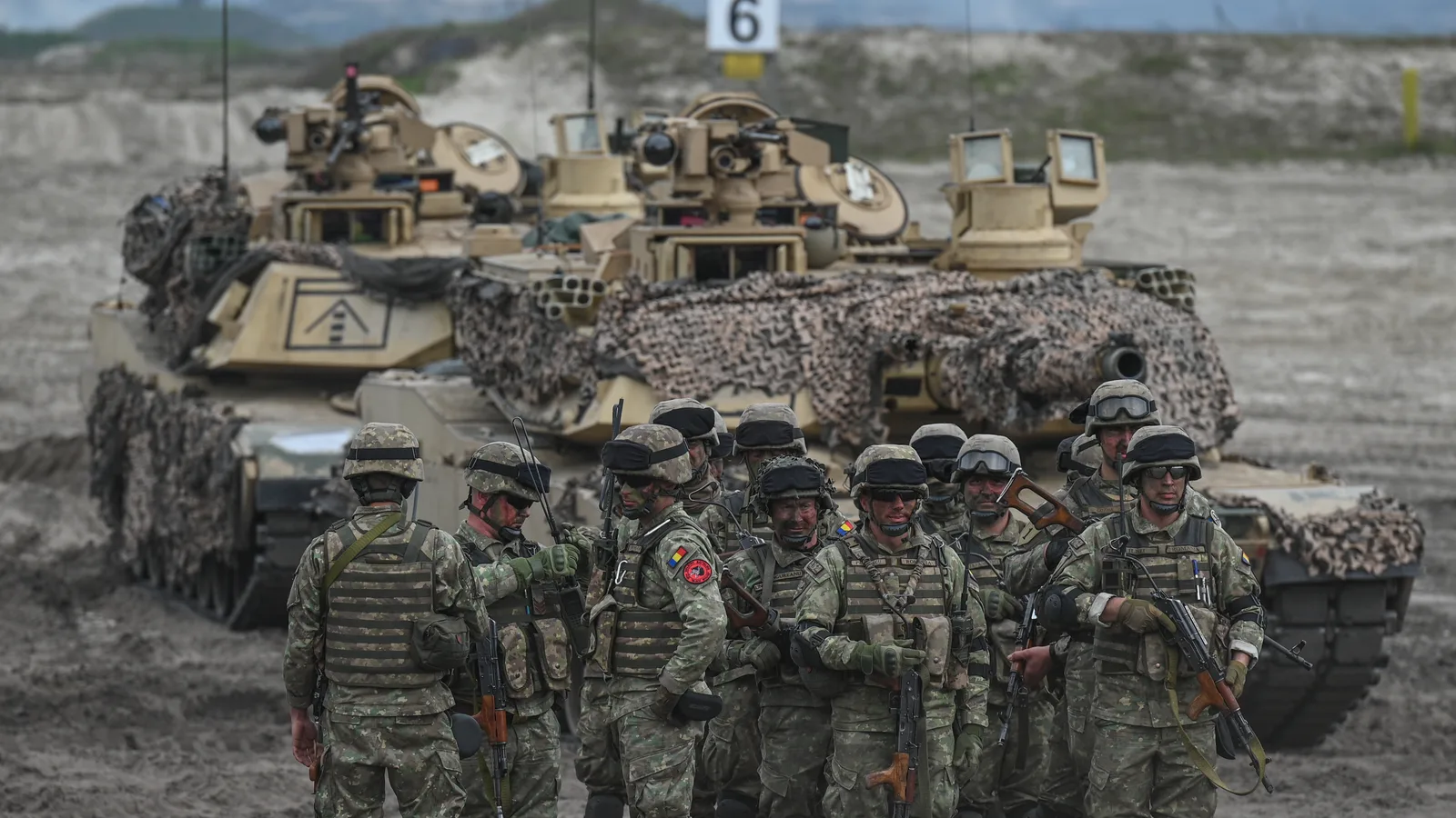 Soldați echipați pentru exerciții militare în teren accidentat.