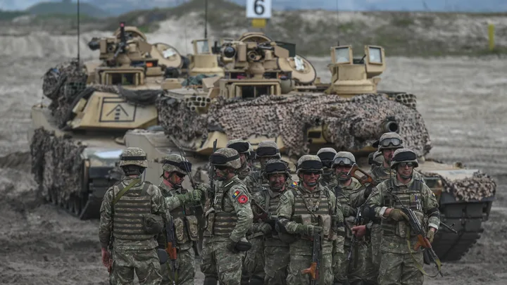 Soldați echipați pentru exerciții militare în teren accidentat.