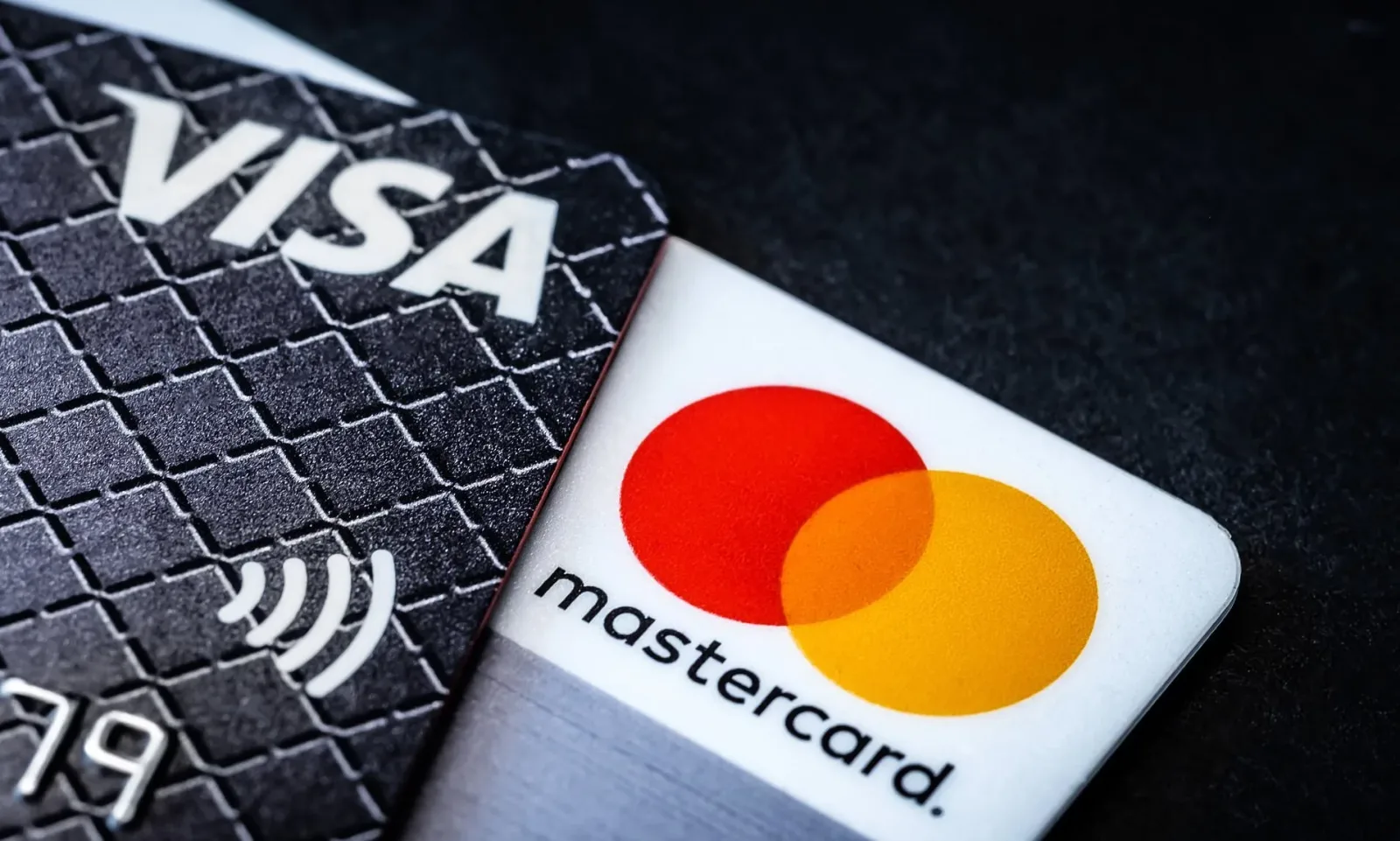 Carduri de plată Visa și Mastercard pe un fundal întunecat.