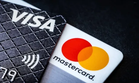 Carduri de plată Visa și Mastercard pe un fundal întunecat.