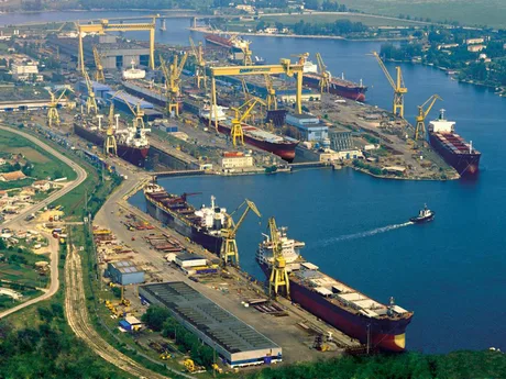 Vedere aeriană a șantierului naval Damen Shipyards din Mangalia, cu nave și echipamente pe apă.